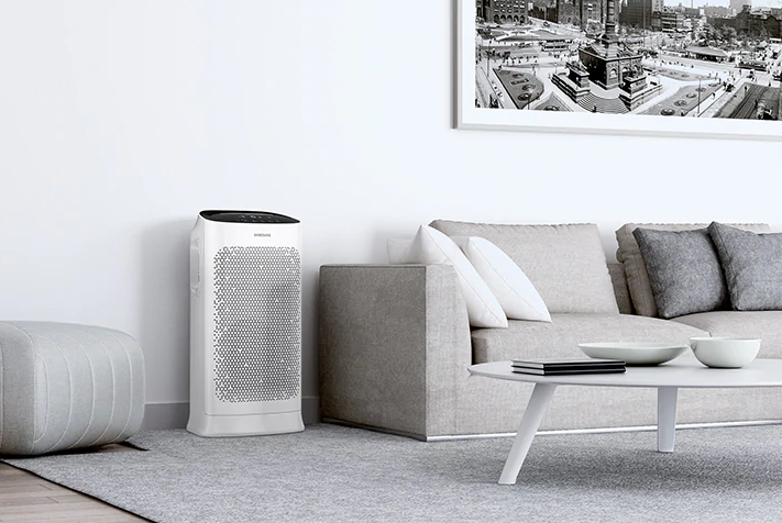 Oczyszczacz powietrza Samsung AX60R5080WD, w pokoju obok kanapy.